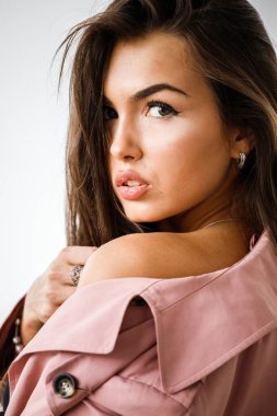 Pembe ceket ayakta beyaz stüdyo arka plan üzerinde giyen güzel esmer kadın portresi portre