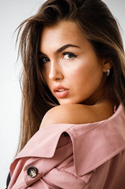 Pembe ceket ayakta beyaz stüdyo arka plan üzerinde giyen güzel esmer kadın portresi portre