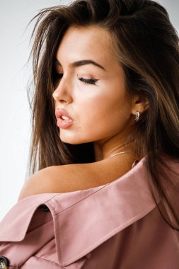 Pembe ceket ayakta beyaz stüdyo arka plan üzerinde giyen güzel esmer kadın portresi portre