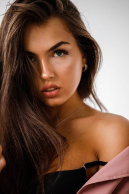 Pembe ceket ayakta beyaz stüdyo arka plan üzerinde giyen güzel esmer kadın portresi portre