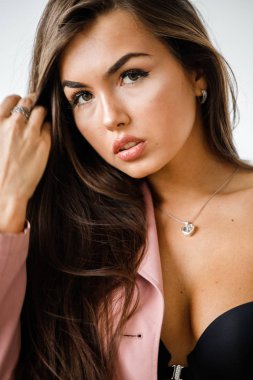 Pembe ceket ayakta beyaz stüdyo arka plan üzerinde giyen güzel esmer kadın portresi portre