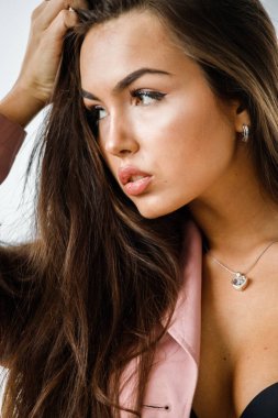 Pembe ceket ayakta beyaz stüdyo arka plan üzerinde giyen güzel esmer kadın portresi portre