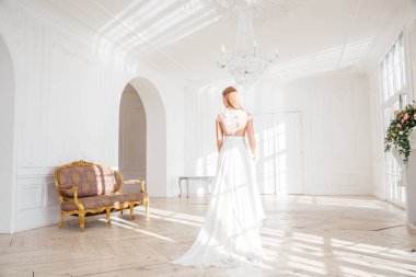 Güzel sarışın kadın beyaz iç arka plan ayakta beyaz elbise moda çekim
