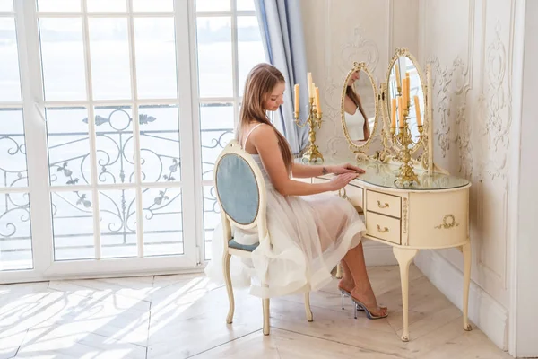 白いインテリアの背景に 椅子に座って白いドレスで美しい金髪女性のファッション撮影 — ストック写真