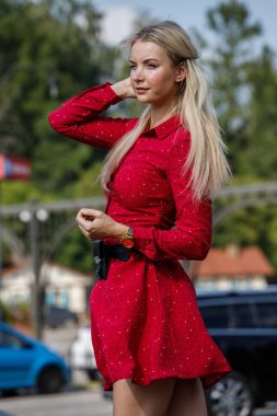 Gündüz caddenin üzerinde kırmızı elbise duran güzel sarışın kadın portresi açık moda