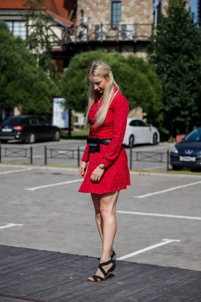 Gündüz caddenin üzerinde kırmızı elbise duran güzel sarışın kadın portresi açık moda