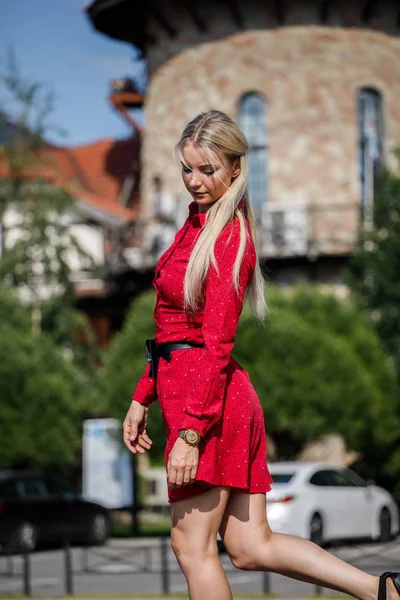 Gündüz caddenin üzerinde kırmızı elbise duran güzel sarışın kadın portresi açık moda