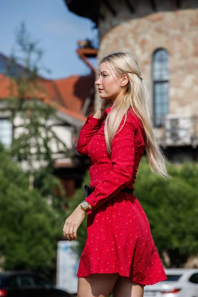 户外时装肖像美丽的金发女郎穿着红色礼服站在城市街道上白天 — 图库照片