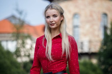 Gündüz caddenin üzerinde kırmızı elbise duran güzel sarışın kadın portresi açık moda