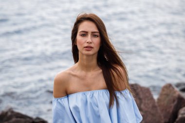 Şort ve tişört ayakta gündüz kayalık kumsalda giyen güzel genç kahverengi saçlı kadın açık atış