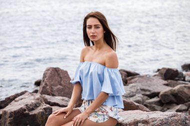 Şort ve tişört ayakta gündüz kayalık kumsalda giyen güzel genç kahverengi saçlı kadın açık atış