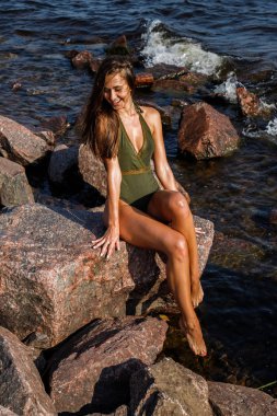 Güneş ışığı güzel esmer kadın portresi. Gündüz kayalık plaj üzerinde mayo modeli