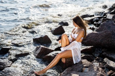 Güneş ışığı güzel esmer kadın portresi. Gündüz kayalık plaj beyaz iç çamaşırı modeli