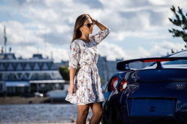 Çiçekler beyaz elbiseli güzel genç kadın açık bir kadeh. Gündüz, modern spor araba Caddesi üzerinde yakın kadın modeli ayakta