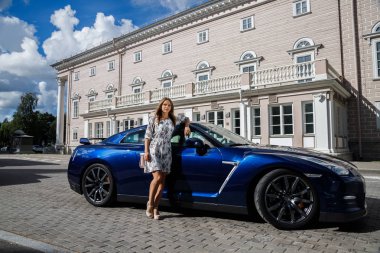 Çiçekler beyaz elbiseli güzel genç kadın açık bir kadeh. Gündüz, modern spor araba Caddesi üzerinde yakın kadın modeli ayakta