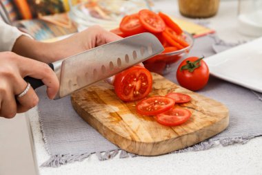 Erkek closeup bıçak ile kesme domates salatası ahşap tahta üzerinde eller