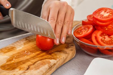 Erkek closeup bıçak ile kesme domates salatası ahşap tahta üzerinde eller