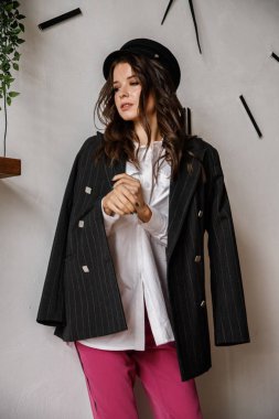 Moda güzellik esmer model giyen portre siyah ceket, beyaz gömlek ve pembe pantolon. Genç güzel kadın lüks daireler iç poz