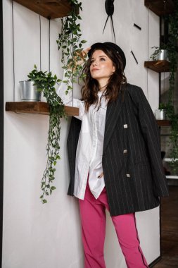 Moda güzellik esmer model giyen portre siyah ceket, beyaz gömlek ve pembe pantolon. Genç güzel kadın lüks daireler iç poz