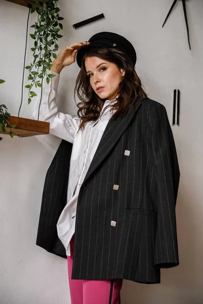 Fashion portrait of beauty brunette model wearing black jacket, white shirt and pink pants. Young beautiful woman posing in luxury apartments interior