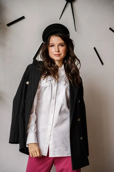 Fashion portrait of beauty brunette model wearing black jacket, white shirt and pink pants. Young beautiful woman posing in luxury apartments interior