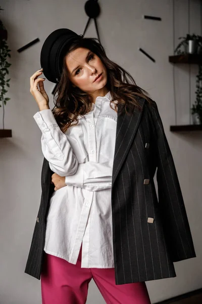 ファッション肖像美ブルネットのモデル着用の黒ジャケット 白シャツとピンク色のズボン 若い美しい女性が高級アパートのインテリアでポーズ — ストック写真