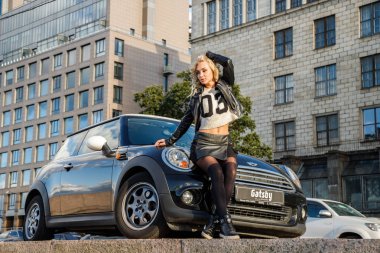 Modern arabanın üzerine eğilerek güzellik kadın açık portresi. Küçük siyah araba yakın duran trendy kıyafetler şık kadın modeli 