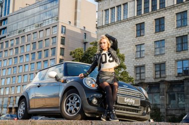 Modern arabanın üzerine eğilerek güzellik kadın açık portresi. Küçük siyah araba yakın duran trendy kıyafetler şık kadın modeli 