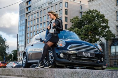 Modern arabanın üzerine eğilerek güzellik kadın açık portresi. Küçük siyah araba yakın duran trendy kıyafetler şık kadın modeli 