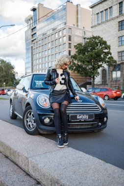 Modern arabanın üzerine eğilerek güzellik kadın açık portresi. Küçük siyah araba yakın duran trendy kıyafetler şık kadın modeli 