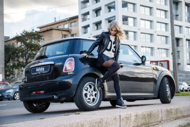 Modern arabanın üzerine eğilerek güzellik kadın açık portresi. Küçük siyah araba yakın duran trendy kıyafetler şık kadın modeli 