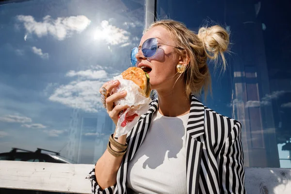 サングラス ストライプ ジャケット シャツ食べるサンドイッチ アウトドアを身に着けている素敵なブロンドの女の子の肖像画 — ストック写真