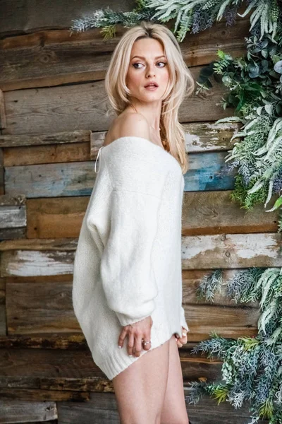 Stüdyo beyaz kazak giyen güzellik kadın portresi. Ahşap duvar arka plan üzerinde duran kadın modeli