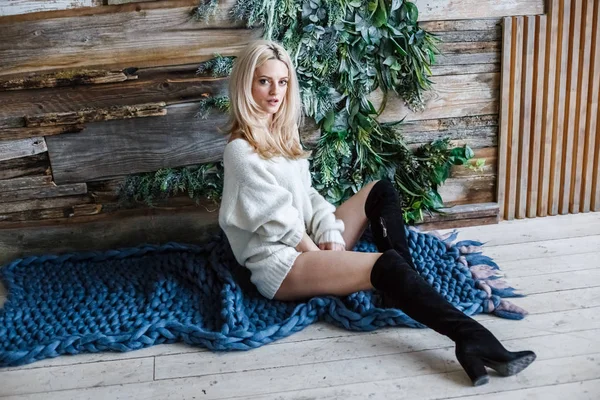 Stüdyo beyaz kazak giyen güzellik kadın portresi. Mavi örme halı, ahşap duvar arka plan üzerinde oturan kadın modeli