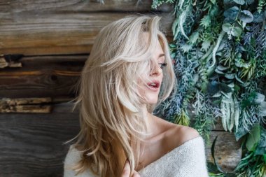 Stüdyo beyaz kazak giyen güzellik kadın portresi. Ahşap katta oturan kadın modeli 