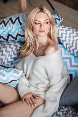 Stüdyo beyaz kazak giyen güzellik kadın portresi. Kadın modeli şık makyaj yatakta yatan ile