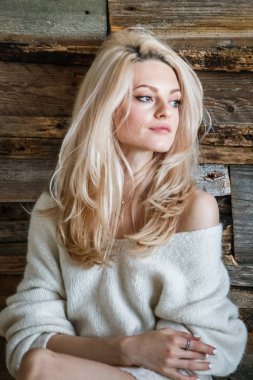 Stüdyo beyaz kazak giyen güzellik kadın portresi. Ahşap katta oturan kadın modeli 