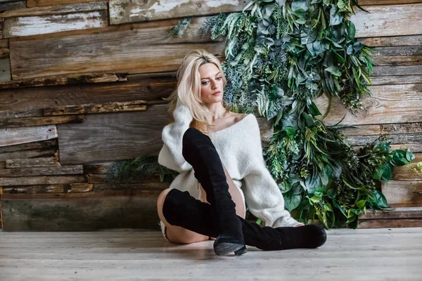 白のセーターを着ている金髪美女のスタジオの肖像画 木製の床の上に横たわる女性モデル — ストック写真