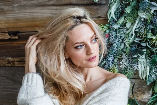 Stüdyo beyaz kazak giyen güzellik kadın portresi. Ahşap katta oturan kadın modeli 