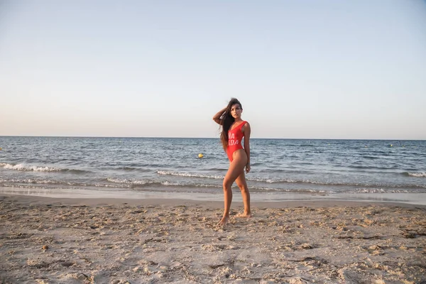 Junge Brünette Frau Rotem Badeanzug Steht Tagsüber Sandstrand — Stockfoto