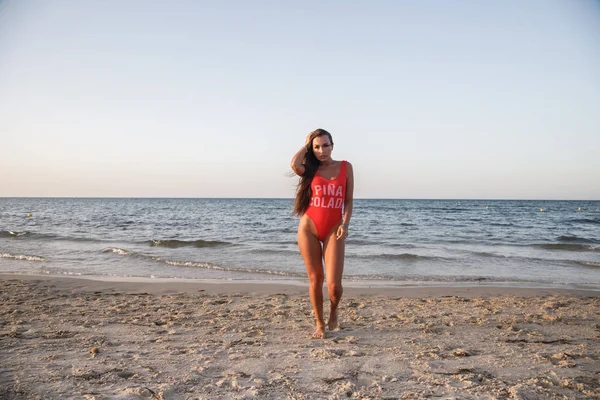 Junge Brünette Frau Rotem Badeanzug Steht Tagsüber Sandstrand — Stockfoto