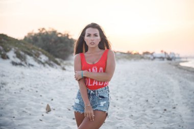 Güzel esmer model gündüz kumsalda duran kırmızı mayo ve kot şort