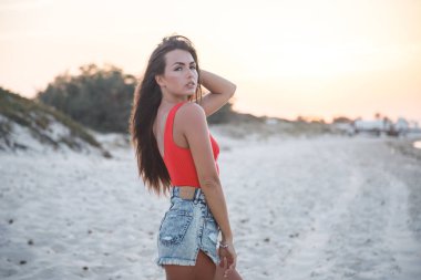 Güzel esmer model gündüz kumsalda duran kırmızı mayo ve kot şort