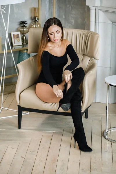 穿着黑色衣服的美丽年轻女子的肖像 年轻的模特坐在豪华公寓内部的扶手椅上 — 图库照片