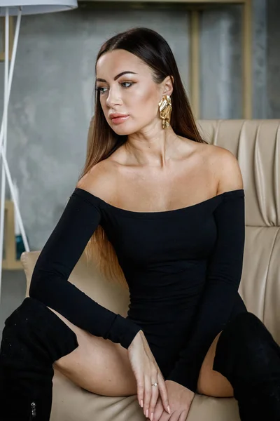 黒い服を着た美しい若い女性の肖像画 高級アパートのインテリアで肘掛け椅子に座って若いモデル — ストック写真