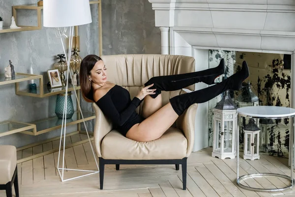 黒い服を着た美しい若い女性の肖像画 高級アパートのインテリアで肘掛け椅子に座って若いモデル — ストック写真
