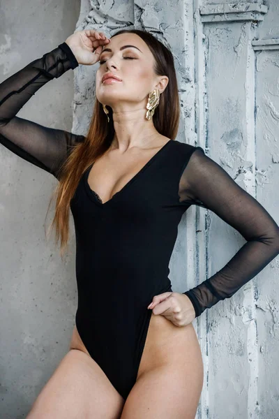 黒い服を着た美しい若い女性の肖像画 若いモデル高級アパートのインテリアの壁の近くに立っています — ストック写真