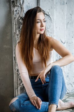 Mavi jeans ve bej t-shirt güzel genç kadın portresi. Lüks daireler iç duvar yakın katta oturan genç modeli