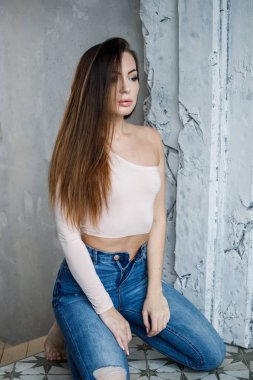 Mavi jeans ve bej t-shirt güzel genç kadın portresi. Lüks daireler iç duvara yakın duran genç model