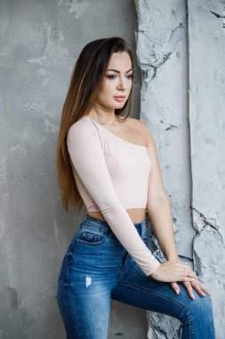 Mavi jeans ve bej t-shirt güzel genç kadın portresi. Lüks daireler iç duvara yakın duran genç model